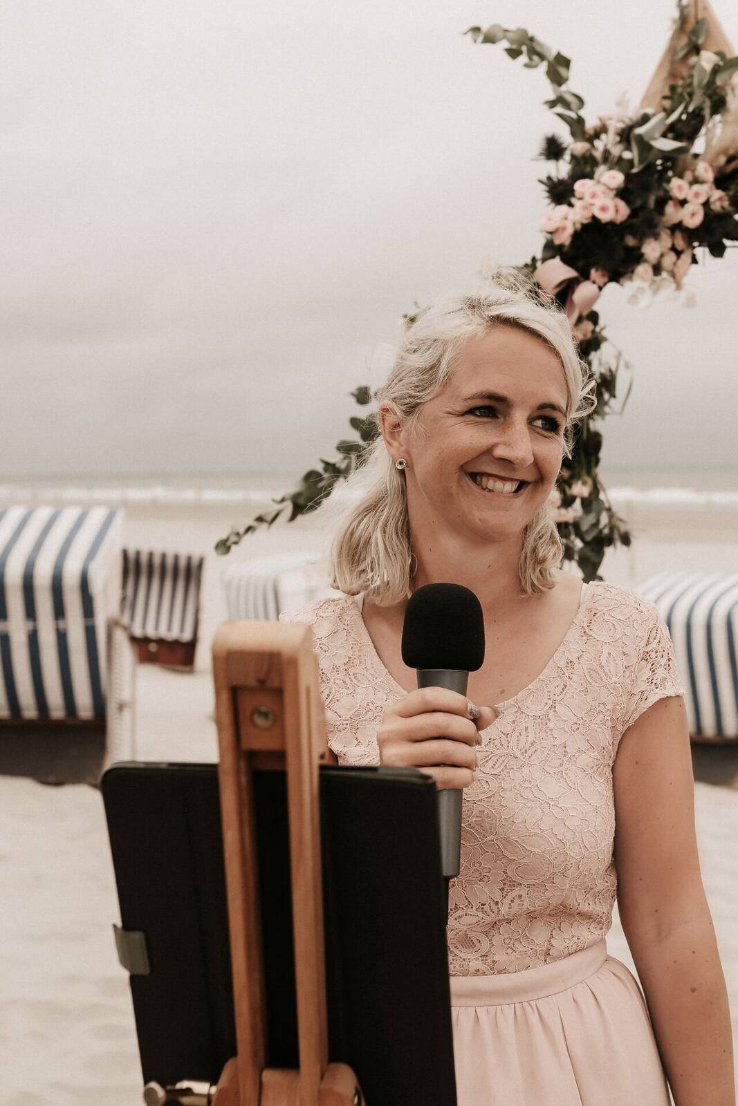 Trauredner:in mit Mikrofon bei einer Strandzeremonie